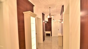 A hallway with wooden paneling, a marble floor, and a chandelier. - Vila Ključe Apartmnets (Bled)