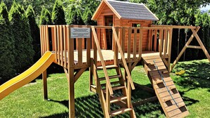 A wooden play structure with a slide and a small house-like building. - Vila Ključe Apartmnets (Bled)