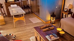 Et hyggeligt værelse med trægulv, en rød sofa, et træbord med magasiner, en lille måtte og en glasdør, der fører ud til en balkon.