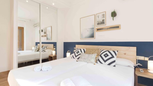 Een hotelkamer met een groot bed, een spiegel, nachtkastjes en een kunstwerk aan de muur.