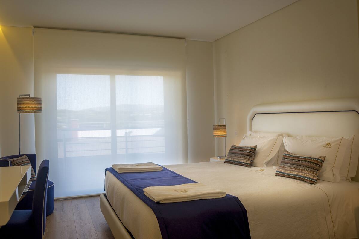 A hotel room with a bed, a desk, and a chair.