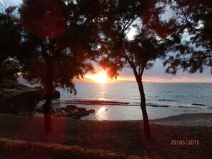 A beach scene with trees, rocks, and the ocean. - Ravdoucha Beach Studios (Platanias)