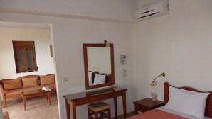Habitación de hotel con cama, escritorio, silla, espejo, mesita de noche, lámpara y ventana.