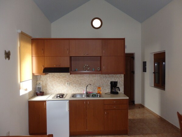 A compact kitchen with wooden cabinets, a white refrigerator, a sink, and a coffee maker.