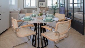 A modern dining area with a round table, four chairs, and a hanging light fixture. - Liiiving in Porto| Luxury Beachfront Apartment III (Porto)