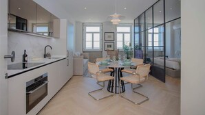 A modern kitchen with a dining area, large windows, and a view of the outdoors. - Liiiving in Porto| Luxury Beachfront Apartment III (Porto)