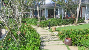 A well-maintained garden pathway leading to a building with a tiled roof and large windows. - Kingo Retreat Resort (Phu Quoc)