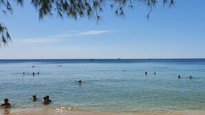 A beach scene with clear water and people swimming. - Kingo Retreat Resort (Phu Quoc)