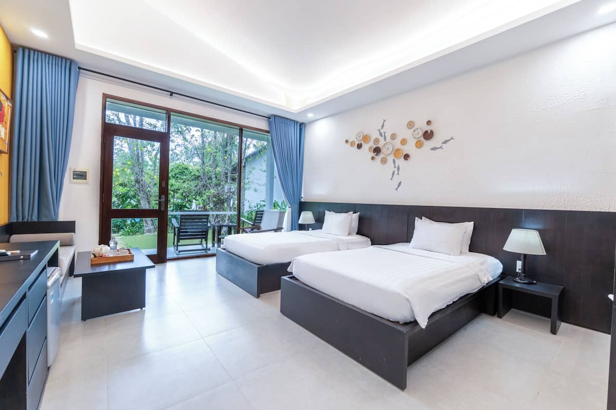 A modern hotel room with two beds, a desk, and a balcony.