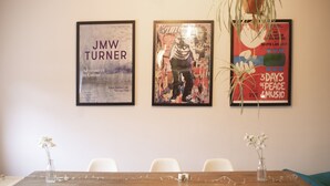 A conference room with a wooden table, white chairs, and two vases with flowers. Three framed posters are displayed on the wall. - Old Town Grade II Listed 2 Bed (Margate)