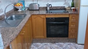 Una cocina con armarios de madera, encimera de granito, fregadero, tostadora, cafetera y lavavajillas.