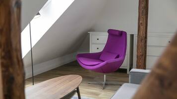 Una habitación moderna con techo inclinado, una silla morada, una mesa de madera y un aparador blanco.