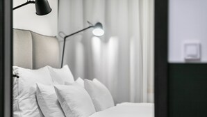 A neatly made bed with white pillows and a black floor lamp in a modern room. - Pytloun Flat Hotel (Liberec)