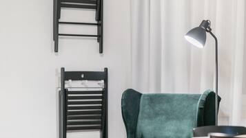 A room with a green armchair, two black chairs, a table, and a floor lamp.