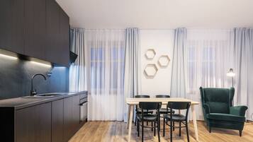 A modern kitchen with dark cabinets, a stainless steel sink, and a dining area with a wooden table and black chairs.
