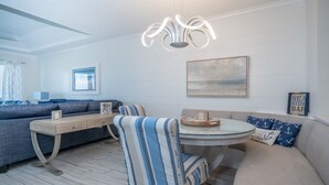 A modern living room with a sofa, a round table, and a striped chair. There is a framed picture on the wall and a ceiling light fixture. - Live in luxury in this penthouse paradise! (Fernandina Beach)
