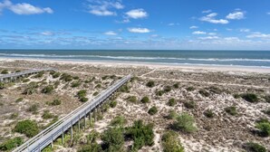 A beach with a wooden boardwalk leading to the shore. - Live in luxury in this penthouse paradise! (Fernandina Beach)