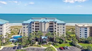 A multi-story hotel with a pool, surrounded by palm trees and a view of the ocean. - Live in luxury in this penthouse paradise! (Fernandina Beach)