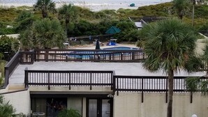 Een pand aan het strand met een zwembad, palmbomen en uitzicht op de oceaan.