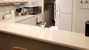 Een moderne keuken met witte kastjes, een centraal eiland en ingebouwde apparatuur.