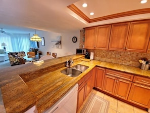Kitchen area with a sink, microwave, and coffee maker, adjacent to a dining space with a table and chairs.