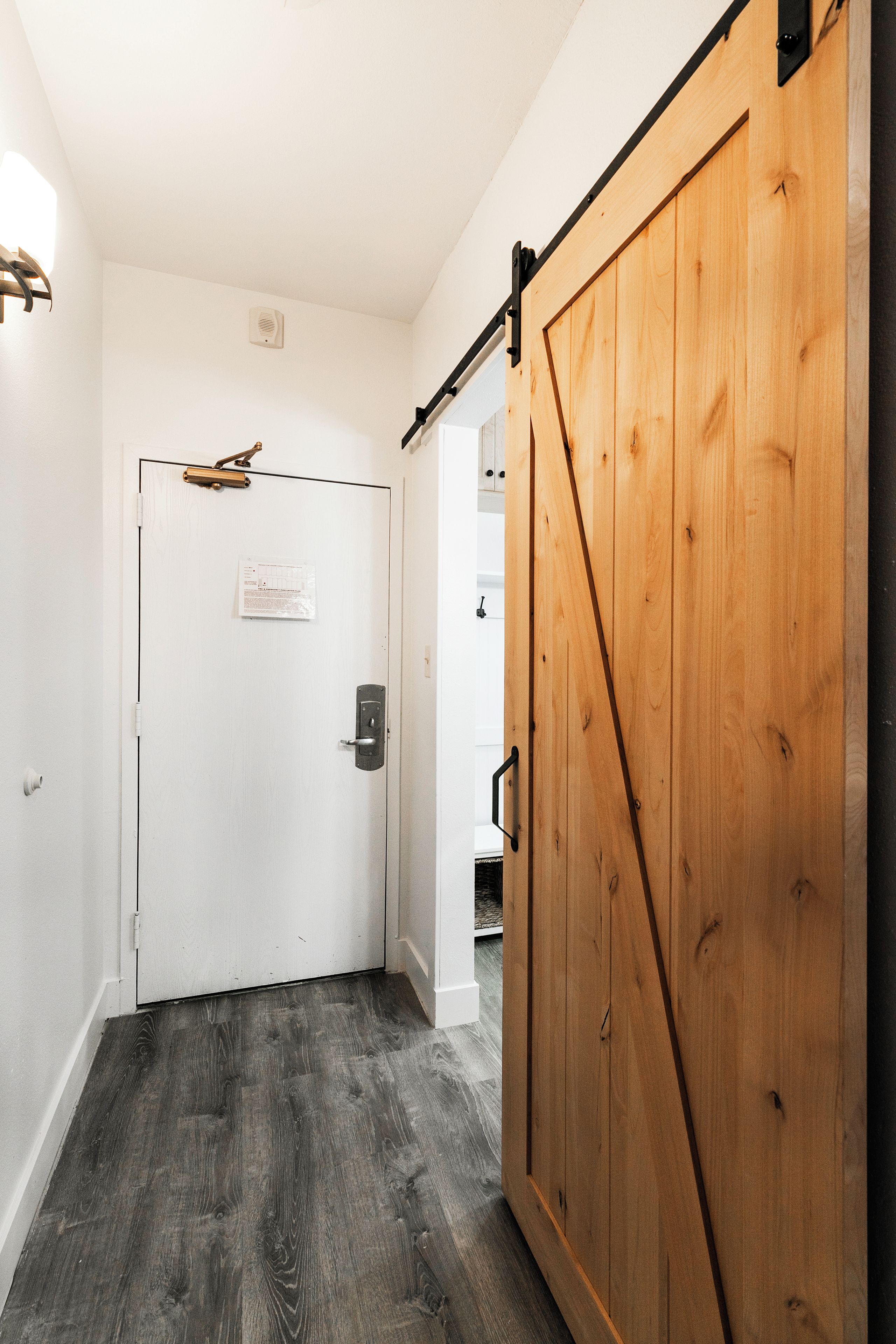 A hallway with a white door, a wooden sliding door, and a dark wooden floor.
