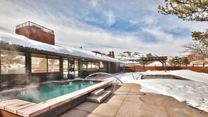 A modern outdoor pool area with a hot tub, surrounded by snow-covered ground and a wooden deck. - Prospector Studio - Slps 4 (Park City)