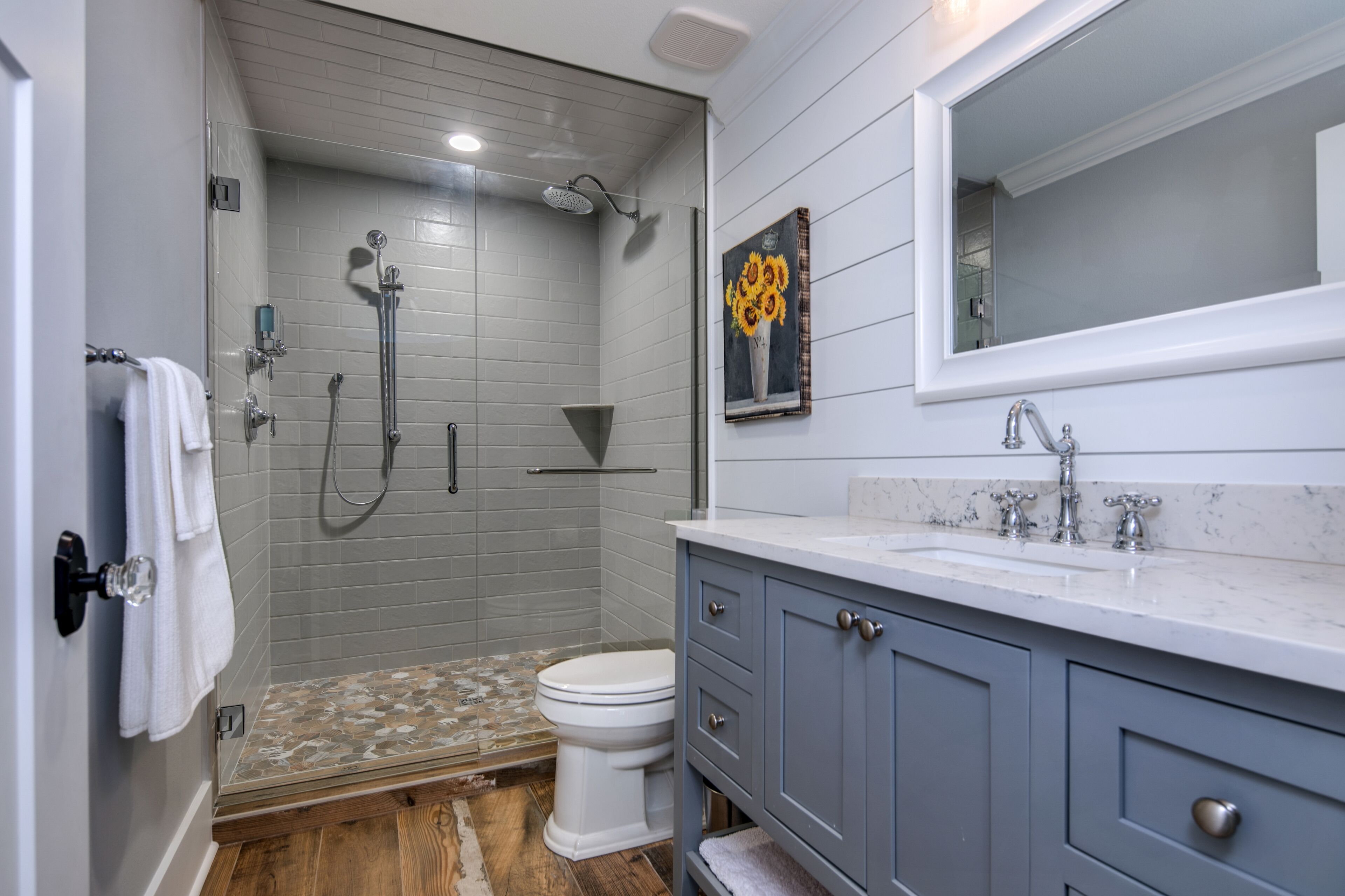 Une salle de bain équipée d’une douche, de toilettes, d’un lavabo et d’un miroir.