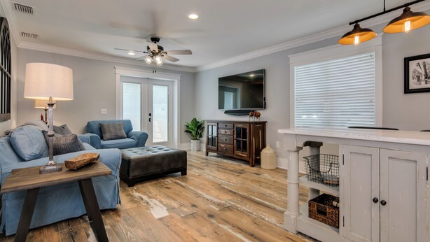A living room with a sofa, coffee table, and a TV mounted on the wall. - The Carlton* 3 min walk to Downtown Mt. Dora!!  (Mt Dora)