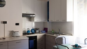 A compact kitchen with white cabinets, a gas stove, a toaster, and a sink.