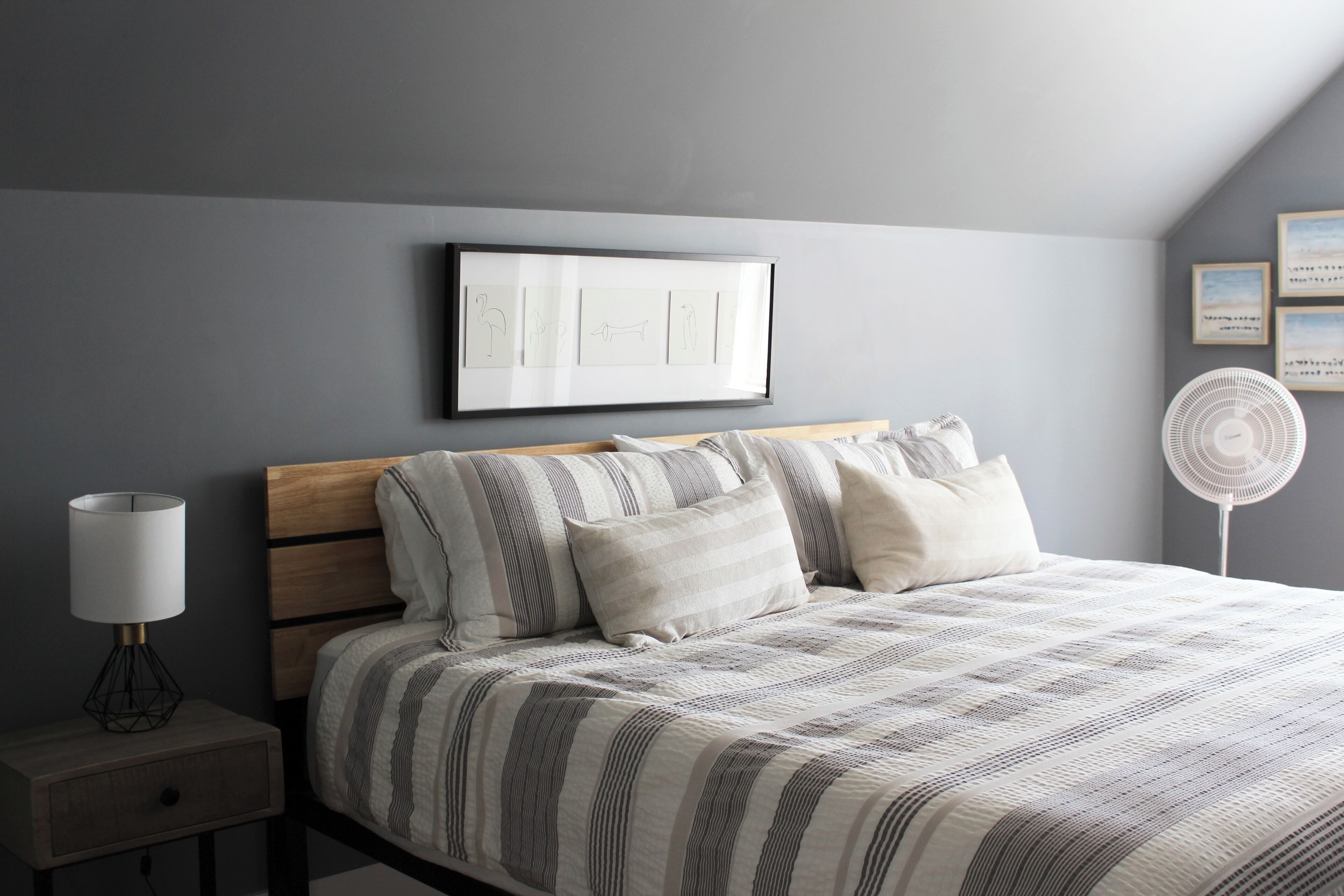 A bedroom with a bed, bedside table, and wall-mounted artwork.