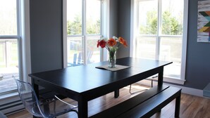 A modern dining area with a dark wooden table, clear plastic chairs, and a vase with flowers.