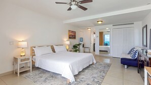 A bedroom with a bed, nightstands, a ceiling fan, a desk, and a chair. - Maho Beach House: Studio Getaway, Oceanfront Vibe (Maho, Sint Maarten)