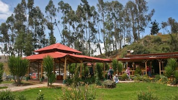 Ein Park mit einem Pavillon, umgeben von üppiger Vegetation und hohen Bäumen.
