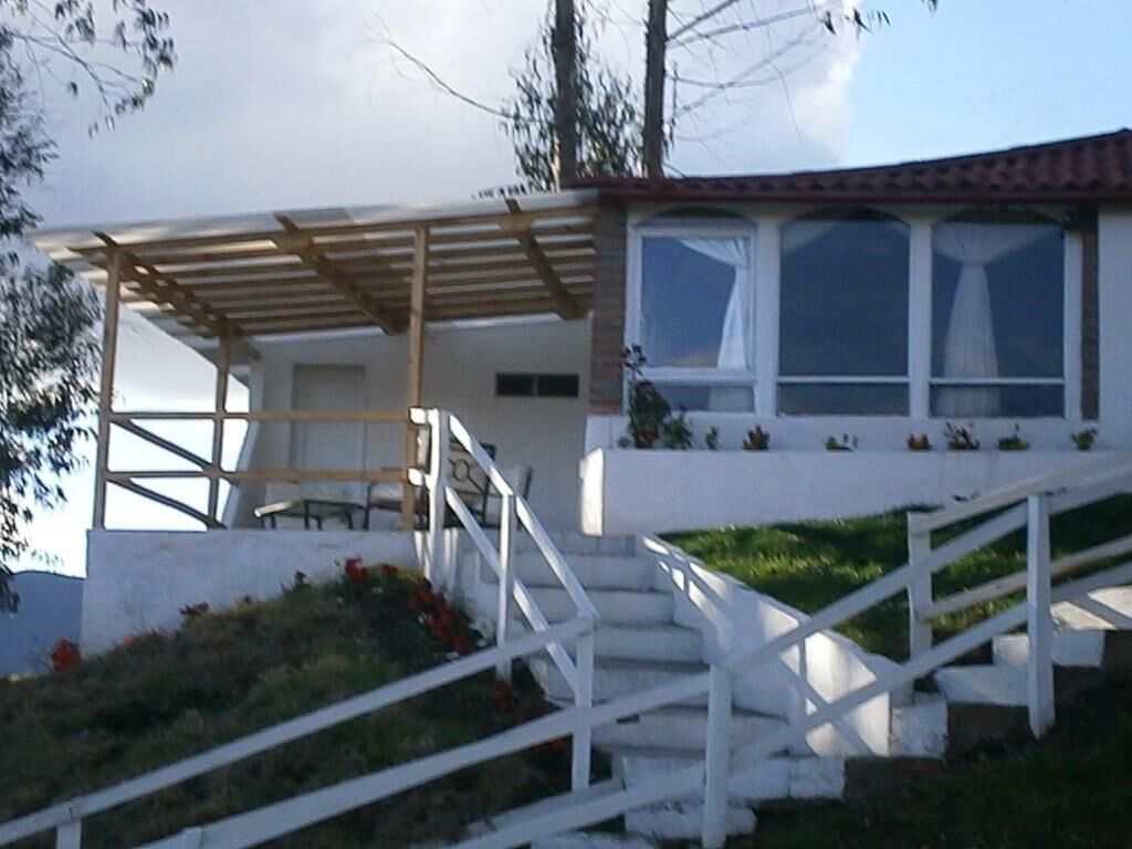 Ein Gebäude mit einer Veranda, einer Treppe und einem fenster mit Vorhängen.
