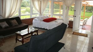 A cozy room with a bed, a sofa, and a coffee table. There is a window with curtains and a view of the outdoors. - Naturaleza Muisca Sas (Guasca)