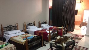 Quarto de hotel com quatro camas de solteiro, um pequeno sofá e um tapete estampado.