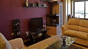 Sala de estar com televisão, sofá e lareira.
