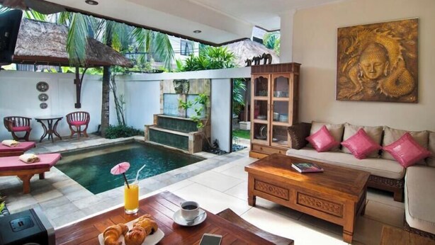 Eine Villa mit Swimmingpool, einem Wohnzimmer mit Sofa und Couchtisch sowie einem Essbereich mit Tisch und Stühlen.