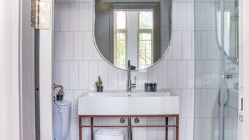 Un baño con lavamanos blanco, espejo y ducha.