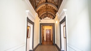 A hallway with a patterned floor, ornate ceiling, and a wooden door at the end.