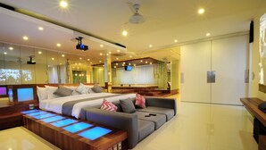 Moderni hotellihuone, jossa on suuri sänky, sohva, hierontapöytä ja televisio.