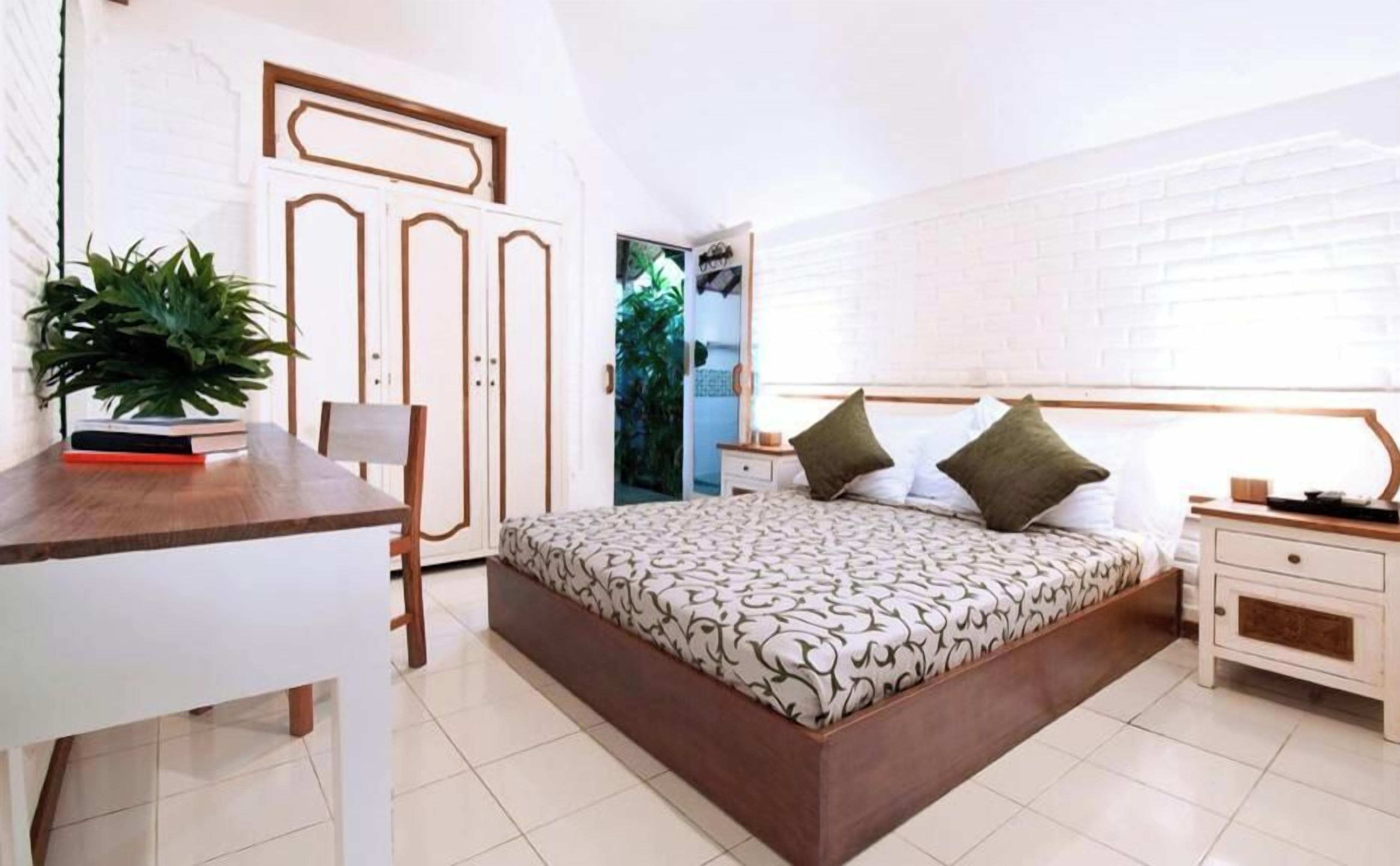 A bedroom with a bed, bedside tables, a desk, and a chair.