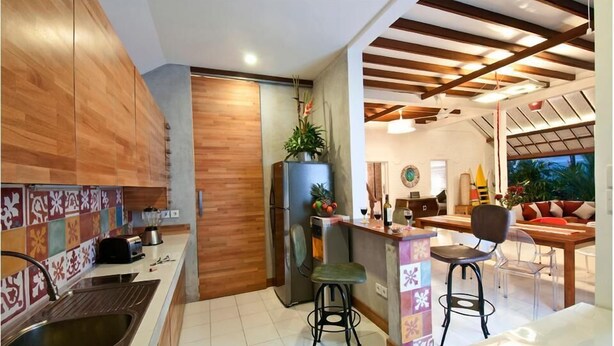 Eine Küche mit Holzausstattung, einem Kühlschrank, einer Spüle und einer Bar mit Hockern.