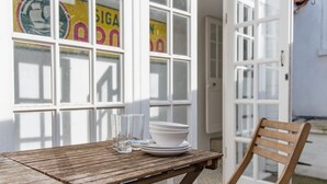 Ein Holztisch mit einer weißen Schüssel und Gläsern, ein Holzbstuhl und eine Tür mit satinierten Glasscheiben.