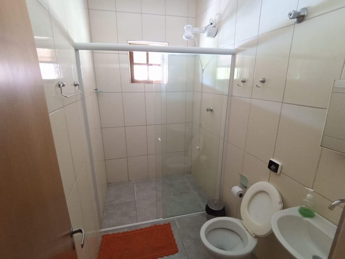 A bathroom with a glass-enclosed shower, a toilet, and a sink.