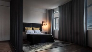 A modern hotel room with a large bed, a nightstand, a framed picture, and a view of the outdoors through a window. - Round loft (azibo) (Macedo de Cavaleiros)