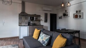 A compact living space with a kitchenette, a dining area, and a sofa with decorative pillows. - Round loft (azibo) (Macedo de Cavaleiros)