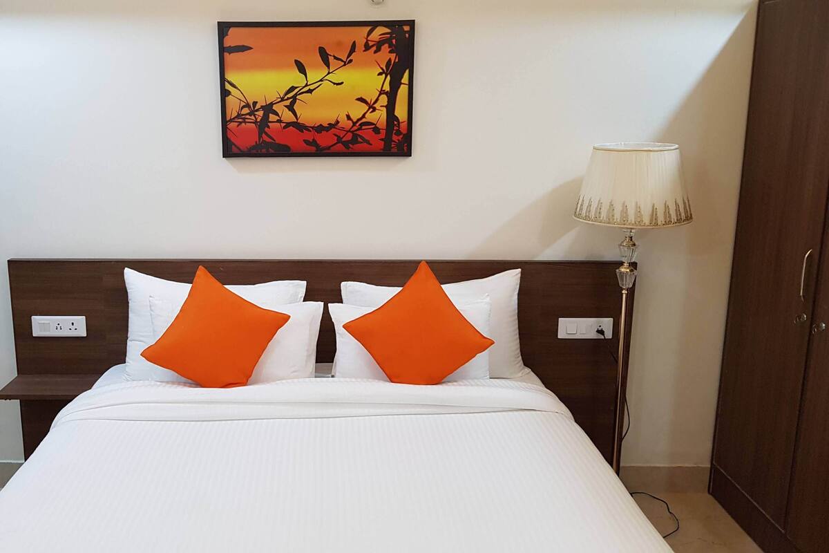 A hotel room with a bed, two nightstands, a lamp, and a painting on the wall.