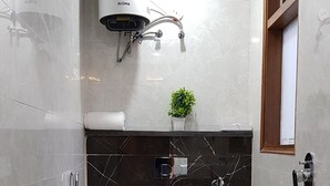 A bathroom with a toilet, a shower, and a sink. - PLLAZIO Residency (Gurugram)